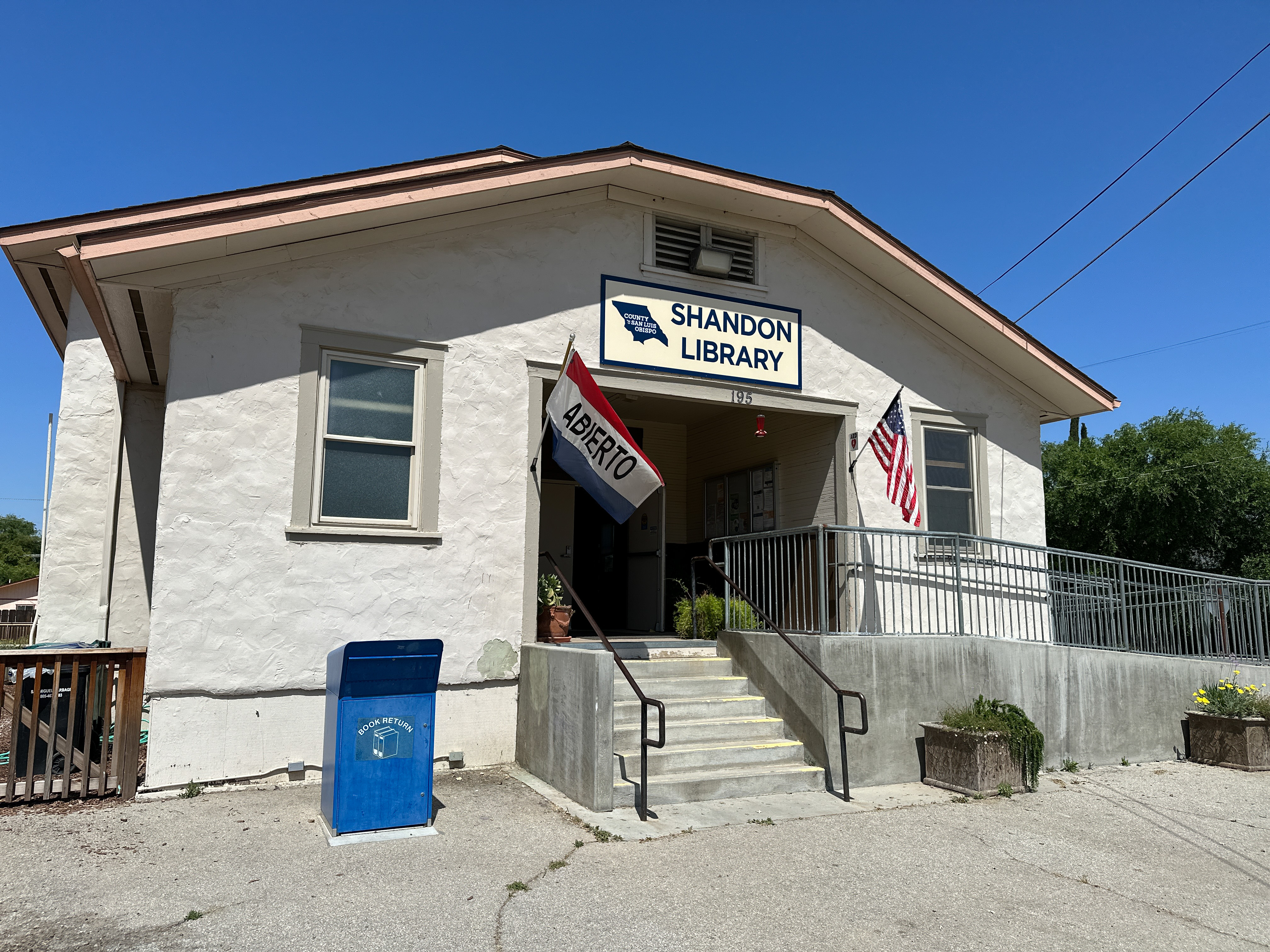 County of San Luis Obispo Public Libraries Shandon, California, location. Beige building with book drop and flag.