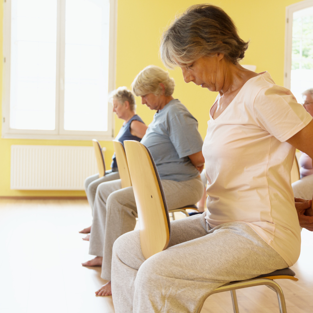 Older woman in chair performing yoga stretch
