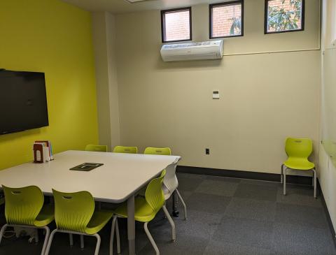 SLO Creative Lab room with TV, computer, table, chairs, and a whiteboard.