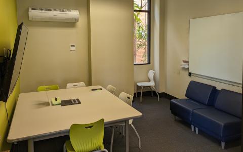 SLO study/meeting room with a TV, table, chairs, and a whiteboard.