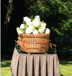 Natural casket on a table with white flowers on top.