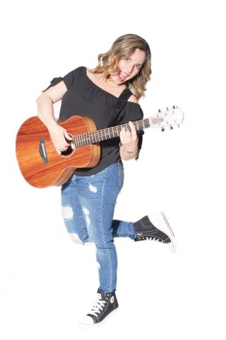 Nathalia holding an acoustic guitar against a white background