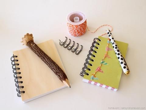 two notebooks with pens on top of them on a white background
