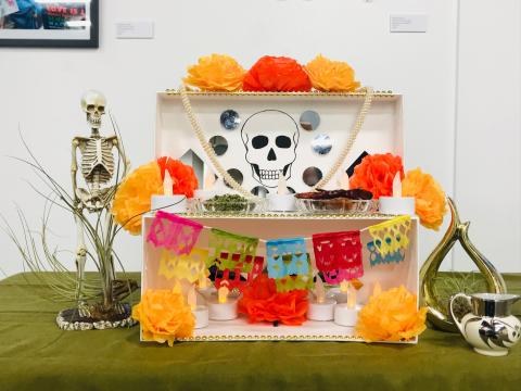 A small altar made from a shoebox and decorated with brightly colored paper and a skull drawing.