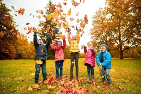 Five kids wearing coats- tossing leaves