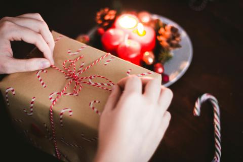 Hands wrapping a package with candy canes