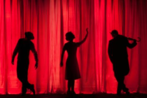 theatre stage with three silhouettes of people