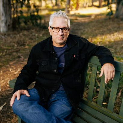 Author Nicholas Belardes sitting on a bench in nature