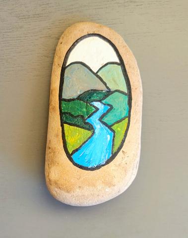 Small rock painted with a peaceful landscape scene. 