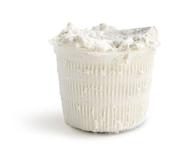 Container of white cheese on a white background.