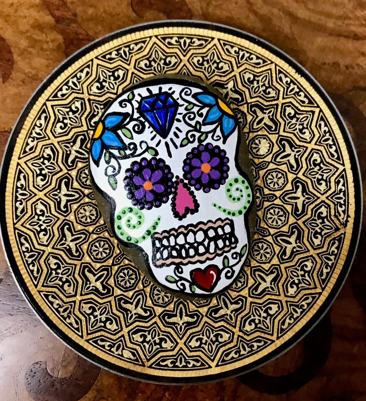 Small rock painted with image of a sugar skull.