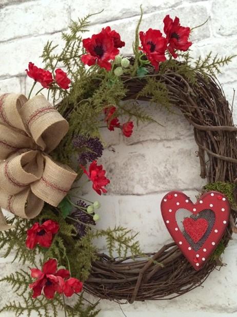 Photo of wreath with bow and red flowers.