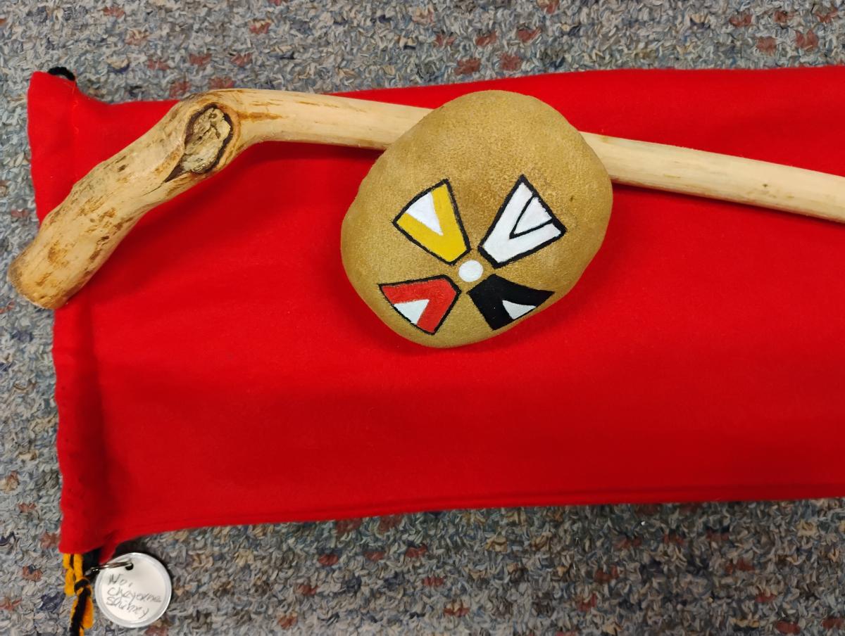 Decorated rock and mallet on a red cloth mat.