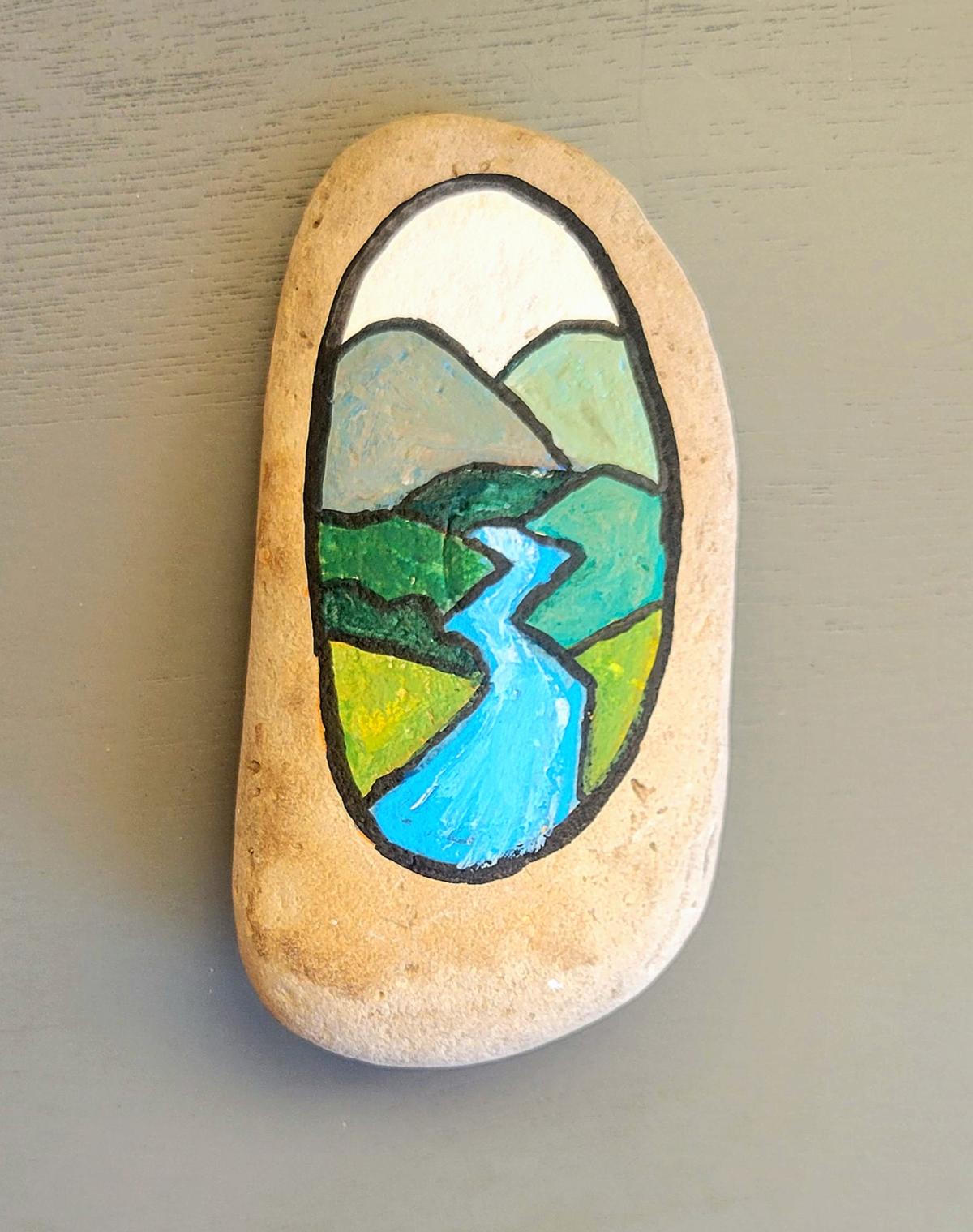 Small rock painted with a peaceful landscape scene. 